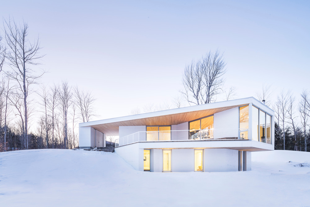 خانه مدرن و سفید با چشم انداز زمستانی در کبک کانادا